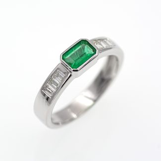 Anillo de oro blanco con esmeralda verde vivo y diamantes.