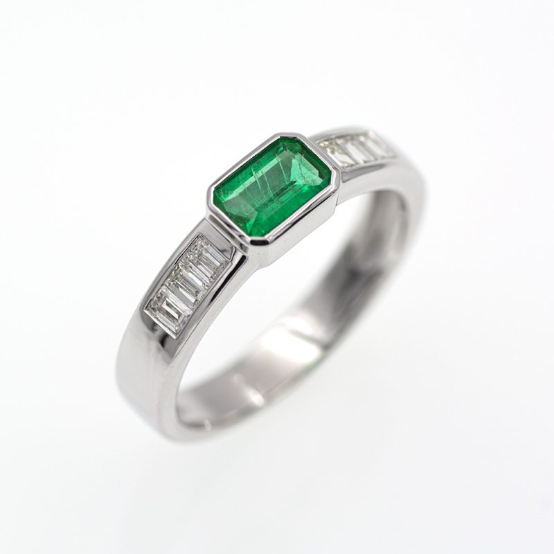 Anillo de oro blanco con esmeralda verde vivo y diamantes.