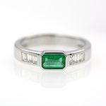 Anillo de oro blanco con esmeralda verde vivo y diamantes.