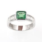 Anillo de oro blanco con esmeralda engastada a bisel y diamantes talla baguette.