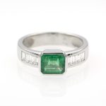 Anillo de oro blanco con esmeralda engastada a bisel y diamantes talla baguette.