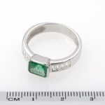 Anillo de oro blanco con esmeralda engastada a bisel y diamantes talla baguette.