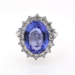Anillo de oro blanco de primera ley con tanzanita natural rodeada de diamantes.