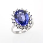 Anillo de oro blanco de primera ley con tanzanita natural rodeada de diamantes.
